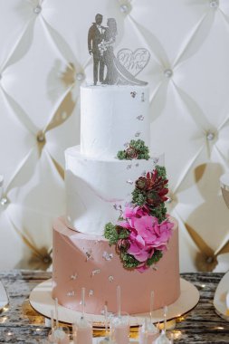 Lezzetli bir düğün. Çiçeklerle süslenmiş beyaz pasta. Şölen için çikolata. Kutlama konsepti. Modaya uygun tatlılar. Şekerli, şekerli bir masa. Meyveler