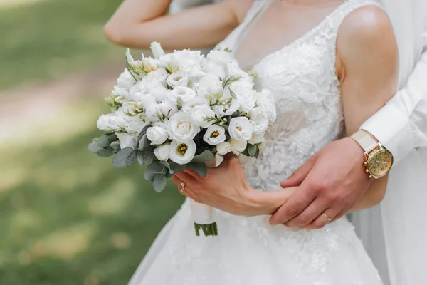 wedding bouquet in the hands of the bride and groom. Emphasis on the wedding bouquet, the bride is out of focus