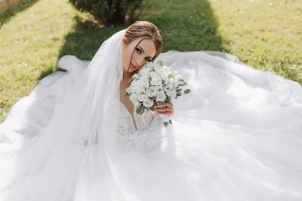 Bruden Bröllopsklänning Med Ett Långt Tåg Och Slöja Håller Bröllopsbukett — Stockfoto