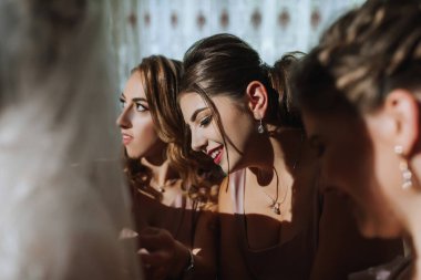 Gelin ve arkadaşlarının portresi. Gelinin arkadaşları gelinin elbisesini bağlar. Esmerler açık omuzlar.