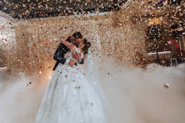 Muhteşem gelin ve şık damat düğün Resepsiyon altın konfeti altında dans. Mutlu evlilik çift ilk dans restoranda gerçekleştirme. Romantik anlar