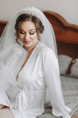 Beyaz etek ve taç giymiş güzel bir gelin yatak odasında yatağında poz veriyor. Düğün için son hazırlıklar. Gelin, damadı bekliyor. Günaydın, gelin..