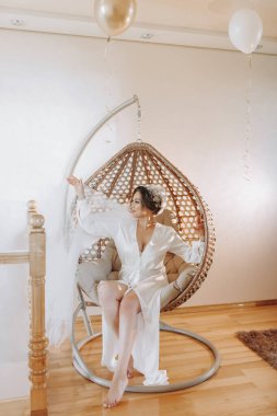 Gelinin portresi. Kızın yüzünde açık bir gölge var. Bornozlu güzel bir gelin hasır bir sandalyede oturur ve poz verir..