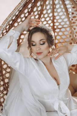 Gelinin portresi. Kızın yüzünde açık bir gölge var. Bornozlu güzel bir gelin hasır bir sandalyede oturur ve poz verir..