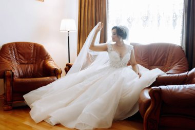 Beyaz elbiseli, güzel saçlı ve makyajlı güzel bir gelin lüks bir kanepede oturuyor. Giyinip düğün törenine hazırlanıyorum.