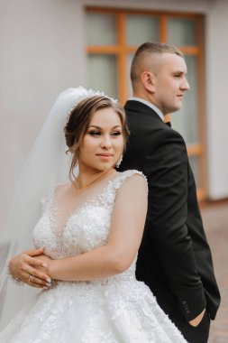 Düğün portresi. Uzun elbiseli esmer bir gelin ve klasik takım elbiseli bir damat peçenin altında onu yanağından öper..