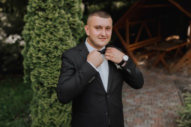 Damadın portresi, yeşil ağaçların arka planına karşı klasik bir takım elbise içinde. Genç bir adam. Tarz. Moda.