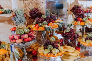 Wedding decorations. Reception. Buffet. Fruits and cheese on plates with bread in boxes. Food bar decorated by flowers and lanters