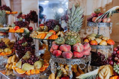 Wedding decorations. Reception. Buffet. Fruits and cheese on plates with bread in boxes. Food bar decorated by flowers and lanters