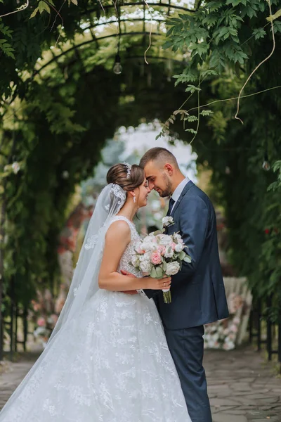 A wedding couple is enjoying the best day of their life against the background of green leaves in the park. Portrait of brides in love in nature