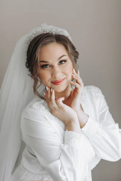 一个漂亮的新娘 身穿长袍 头戴华丽的面纱 有着美丽的头发和妆容 在她的房间里摆姿势 穿上衣服 为婚礼做准备 — 图库照片