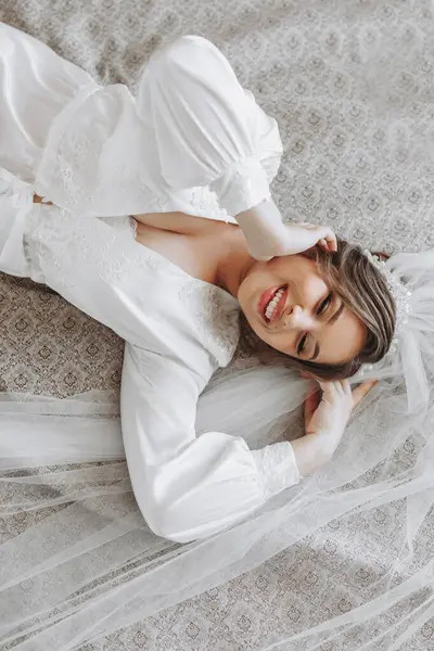 彼女の寝室のベッドに横たわっている白いピグノワールの美しい若い花嫁 結婚式のための最終準備 花嫁は花嫁を待っている 朝から花嫁 — ストック写真