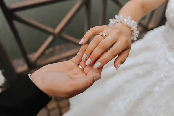 グロムは 湖の背景に対して花嫁の手を優しく保持します 優しいマニキュア 美しい手 手元にあるジュエリー クローズアップ写真 — ストック写真