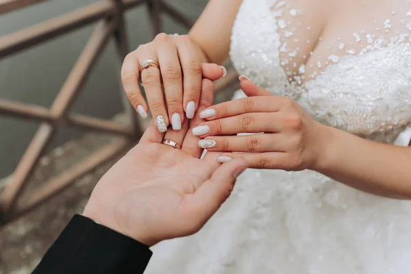 新郎在湖边轻轻握住新娘的手 优雅的修指甲 漂亮的手手上的珠宝 特写照片 — 图库照片