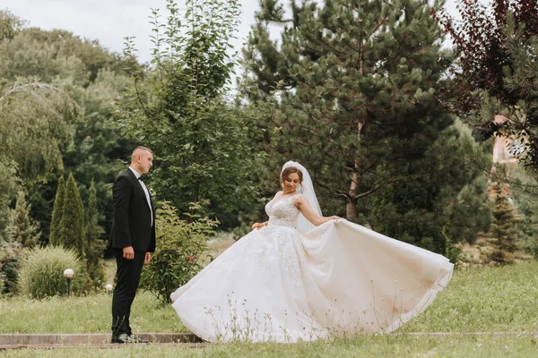 时尚的新郎和可爱的新娘穿着白衣 头戴皇冠 在公园 森林里玩得很开心 婚纱照 广角照片 — 图库照片