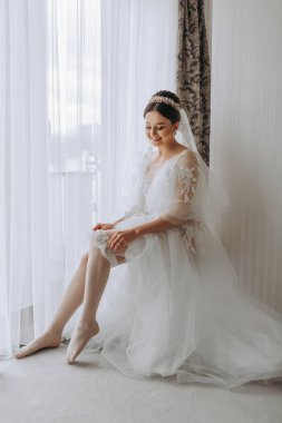 Düğün saç stili ve kafasında şeffaf bir bornoz olan güzel bir kız kraliyet iç mimarisi olan bir otelde düğün hazırlığı yapıyor. Uzun peçe, doğal ışık, portre fotoğrafı.