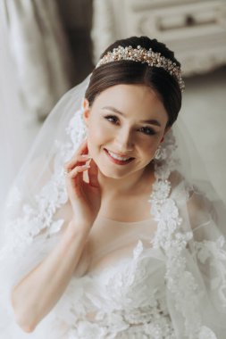 Düğün saç stili ve kafasında şeffaf bir bornoz olan güzel bir kız kraliyet iç mimarisi olan bir otelde düğün hazırlığı yapıyor. Uzun peçe, doğal ışık, portre fotoğrafı.