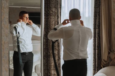 Şık bir damat düğün töreni için hazırlanıyor. Damat sabahı. Otelde beyaz gömlekli bir iş adamı, erkek eli kapalı, damat düğün töreninden önce hazırlanıyor.