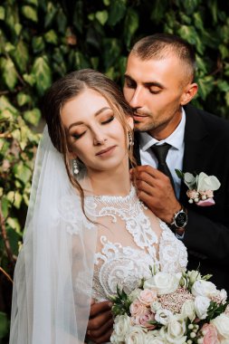 Genç düğün çifti, sonbahar parkında güneşin altında romantik anların tadını çıkarıyor.