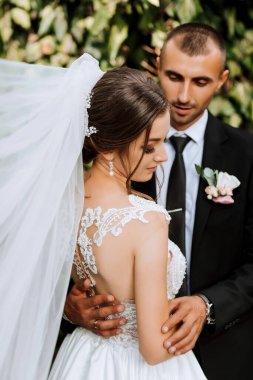 Genç düğün çifti, sonbahar parkında güneşin altında romantik anların tadını çıkarıyor.