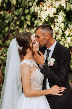 Genç düğün çifti, sonbahar parkında güneşin altında romantik anların tadını çıkarıyor.