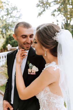 Genç düğün çifti, sonbahar parkında güneşin altında romantik anların tadını çıkarıyor.