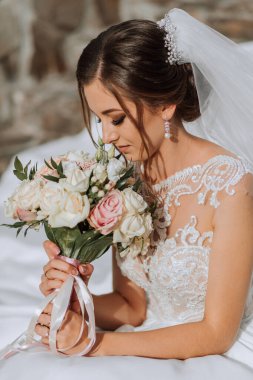 Düğün buketi olan güzel bir gelinin portresi. Güzel saç stili ve profesyonel makyajlı esmer bir kız..