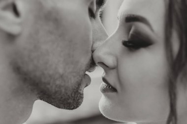 Hassas bir tutkuyla şehvetli bir çift. Bir erkeği öpmek üzere olan bir kadının yakın plan portresi. Aşık çift öpüşüyor. Seksi dudaklar. Siyah beyaz fotoğraf