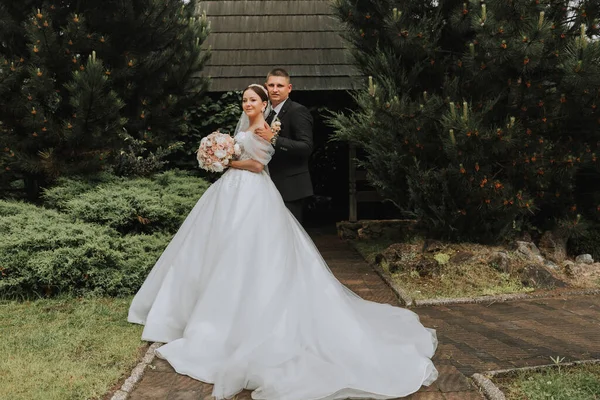 花嫁とグロムは緑の木の背景に対してポーズします 公園内の自然の中でウエディングウォーク — ストック写真