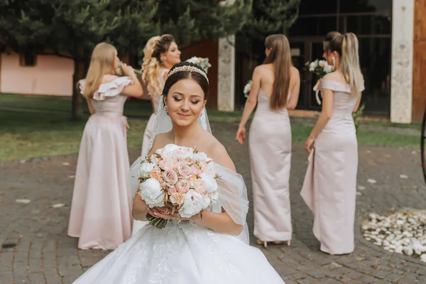 Group portrait of the bride and bridesmaids having fun. Wedding. A bride in a wedding dress and her friends in pink dresses on the wedding day. Stylish wedding in powder color. Concept of marriage.