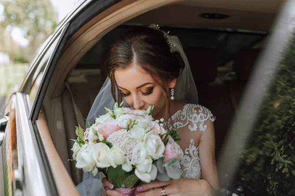 close-up portrait of a rather shy bride in a car window looking at her bouquet of flowers