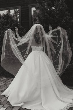 Duvağını tutuyor ve hayatının en güzel gününün tadını çıkarıyor. Güzel gelinlik, profesyonel makyaj ve saç.