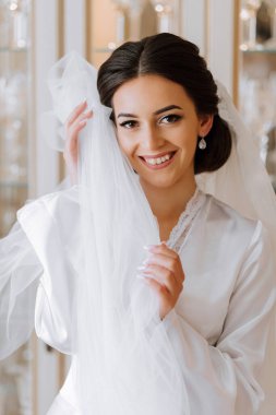 Beyaz cüppeli mutlu esmer gelin uzun peçeli profesyonel makyajlı ve yatak odasında saç stili olan..