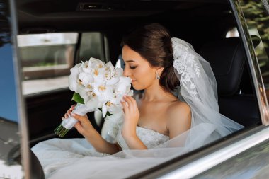 Arabanın camında kameraya bakan utangaç bir gelinin yakın plan portresi.