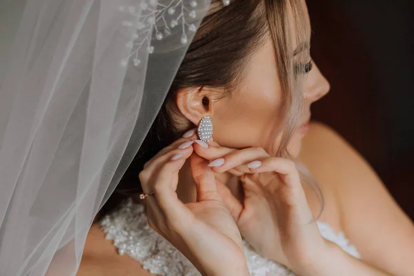 漂亮的新娘戴耳环 一个穿着婚纱的漂亮女孩在室内的特写 婚纱照 — 图库照片