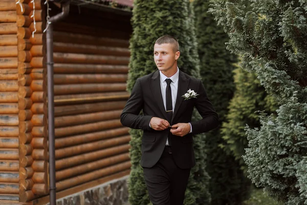 古典的な黒いスーツと白いシャツの男が立って緑の木の近くにポーズしています 男性のスタイル ファッション ビジネスについて — ストック写真