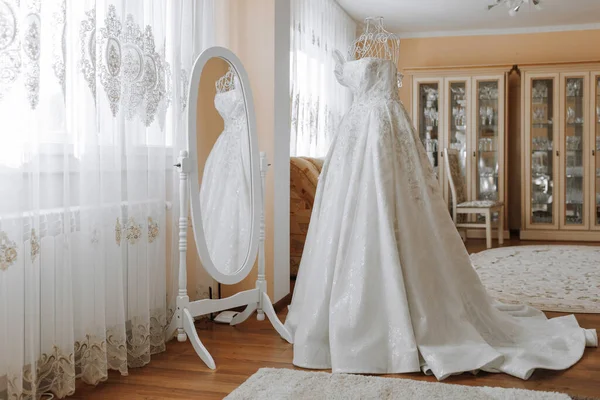 家の内部が付いている部屋の鏡の近くの長い列車が付いている白いウェディング ドレス — ストック写真