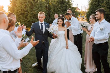 Gelin ve damadın gün batımında aile ve arkadaşlar olarak düğün töreninden sonra koridorda yürürken geniş açı çekimleri.