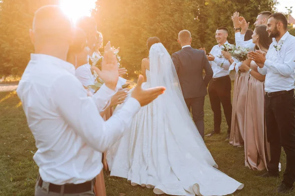 友人や家族が祝うように日没の結婚式の後に通路を歩いた花嫁とグルーミングの広い角度ショット — ストック写真