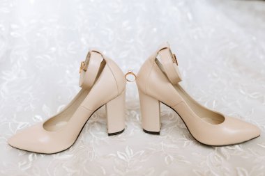 Bej renkli şık ayakkabılar. Elmas bir nişan yüzüğü klasik bir çift düğün ayakkabısının arasında duruyor. Moda. Tarz. Düğün fotoğrafı.