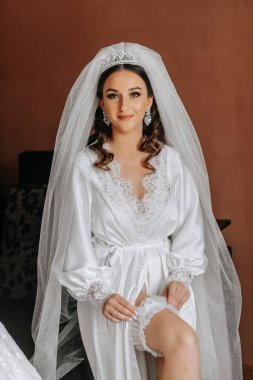 Bir kadın bacağına jartiyer takıyor. Gelin evde kayıp bir jartiyeri elinde tutuyor. Sabah hazırlığı düğün konsepti.