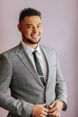 Klasik takım elbiseli sakallı bir adamın portresi. Damat düğün için hazırlanıyor. Adam beyaz bir gömlek ve bir takım elbise giyiyor. Şık damat