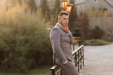 Yakışıklı sakallı adam, gri takım elbiseli damat ve açık havada duran siyah kravat. Düğün portresi. Klasik takım elbiseli bir adam.