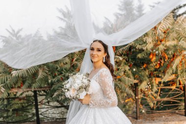 Gelinin bir buketli portresi. Genç ve güzel bir gelin elinde bir buket düğün çiçeği tutuyor. Düğün saçı ve makyaj