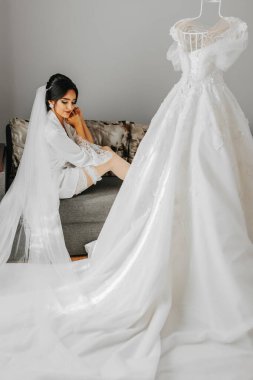 Sabahlık giymiş bir kızın portresi. Profesyonel makyajlı ve fotoğrafçı için uzun peçeli mutlu bir gelin. Gelin düğün için hazırlanıyor.