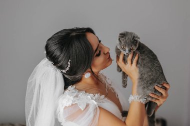 Genç, zarif bir kız kafasında güzel bir peçeyle gelin görünümünde, evcil kedisini kucağında İskoç Katliamı