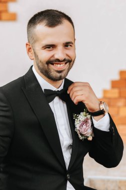 Siyah takım elbiseli ve dışarıda duran siyah papyonlu yakışıklı sakallı damat. Düğün portresi. Klasik takım elbiseli bir adam.