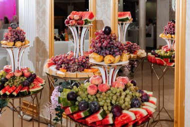 Wedding decorations. Reception. Buffet. Fruits and cheese on plates with bread in boxes. Food bar decorated by flowers and lanters