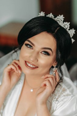 Beyaz cüppeli bir gelinin portresi. Güzel bir saç stili ve kafasında bir taç var. Kameraya bakıyor. Şehvetli şirin gelin pozu. Moda tarzı arasındaki lüks kavramı..