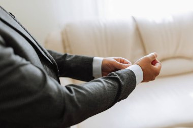 Takım elbiseli bir adam koluna bir şarjör takar ve onu ayarlar. Düğün günü konsepti, moda, iş, erkek tarzı..